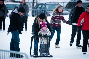 De jeunes parents aprennent à leur fille à patiner.